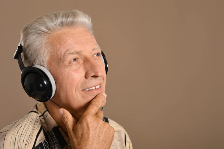 Senior man wearing headphones looking thoughtful