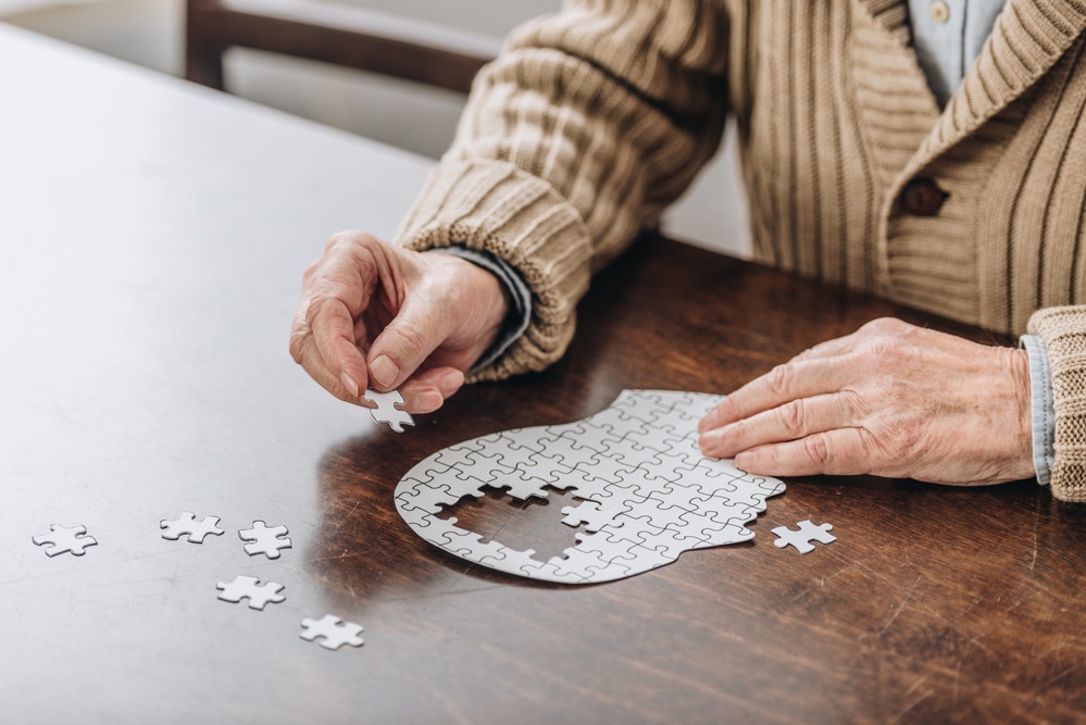 Close-up of senior man completing puzzle shaped like human head