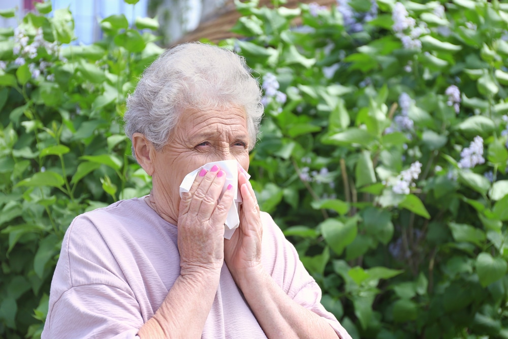 Senior woman blowing nose outside