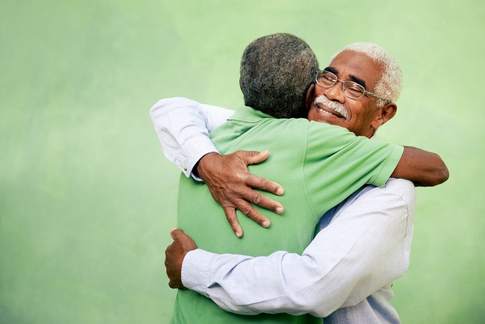 Two senior men smiling and hugging
