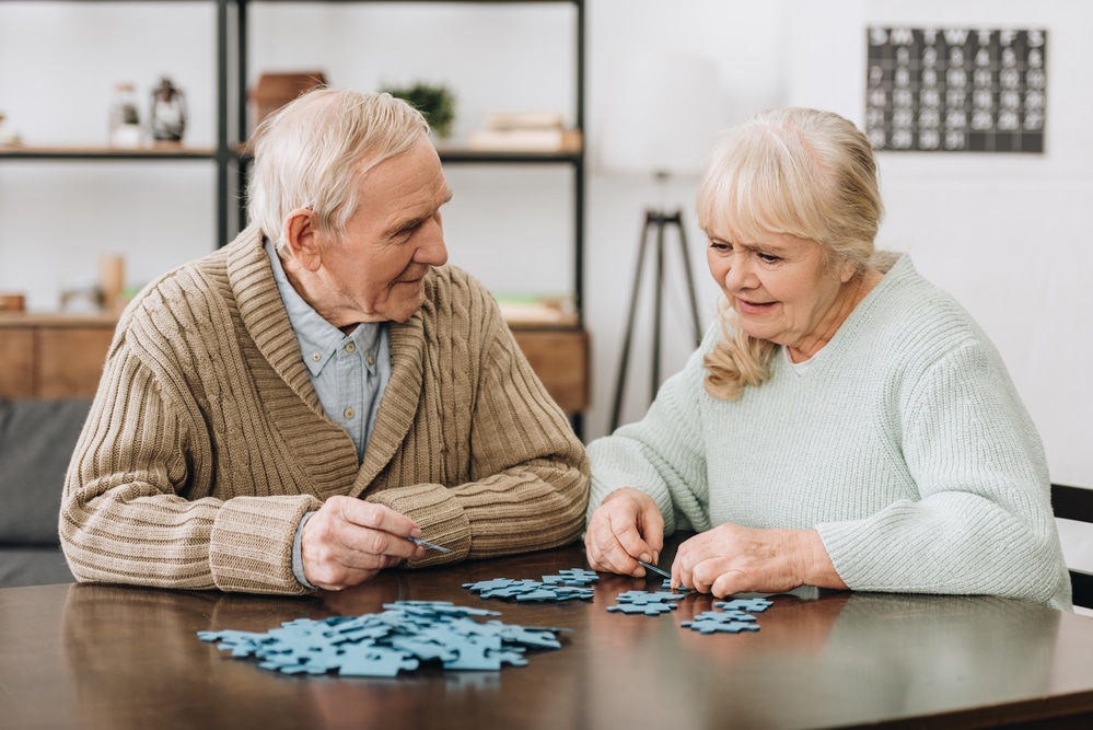 Senior-man-and-woman-completing-puzzle-at-table