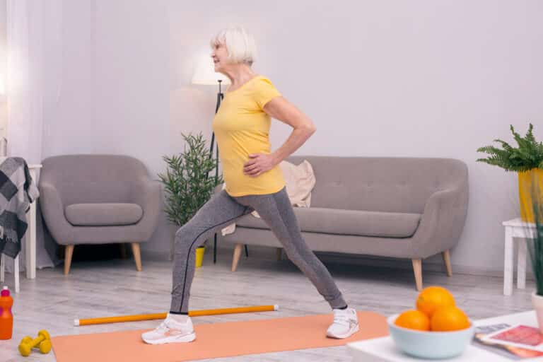 senior woman performing lunges in living room