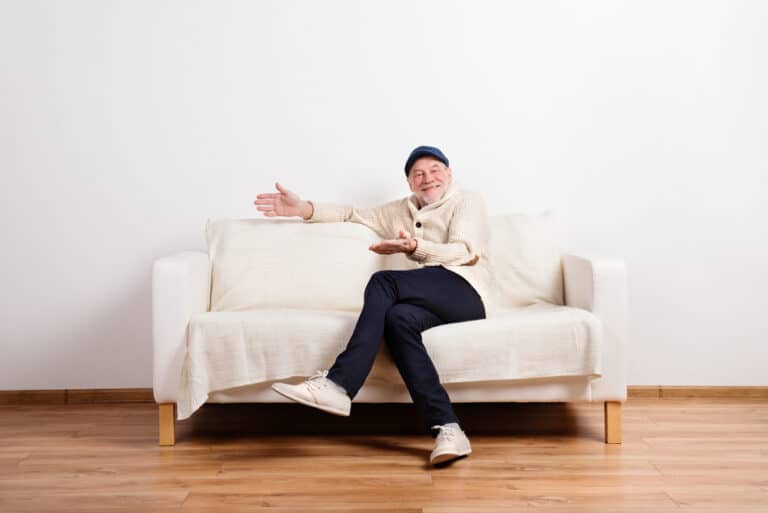 Smiling senior man with crossed legs sitting on couch