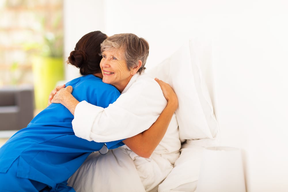 Smiling senior woman hugging young nurse
