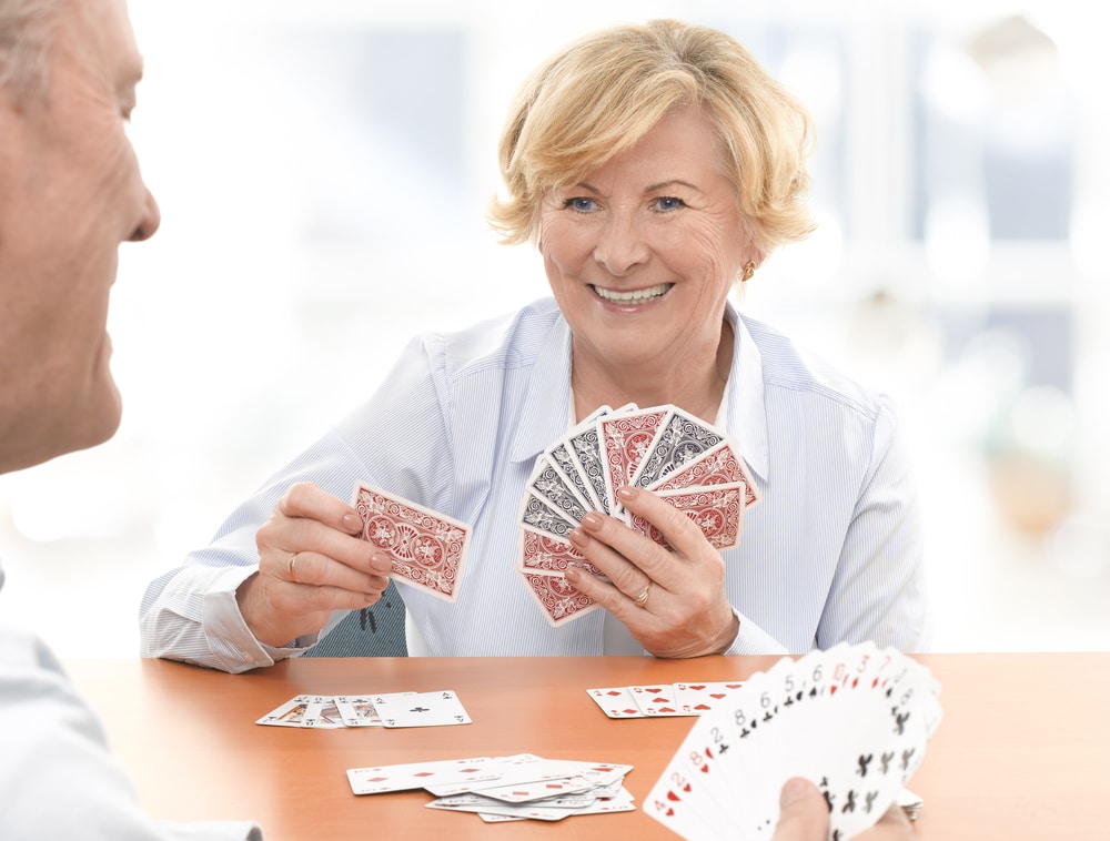 Smiling senior woman playing cards with friend