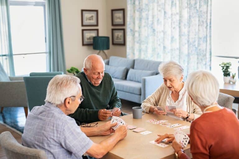 four seniors playing cards in a senior living community