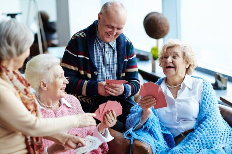 group of laughing seniors playing cards together