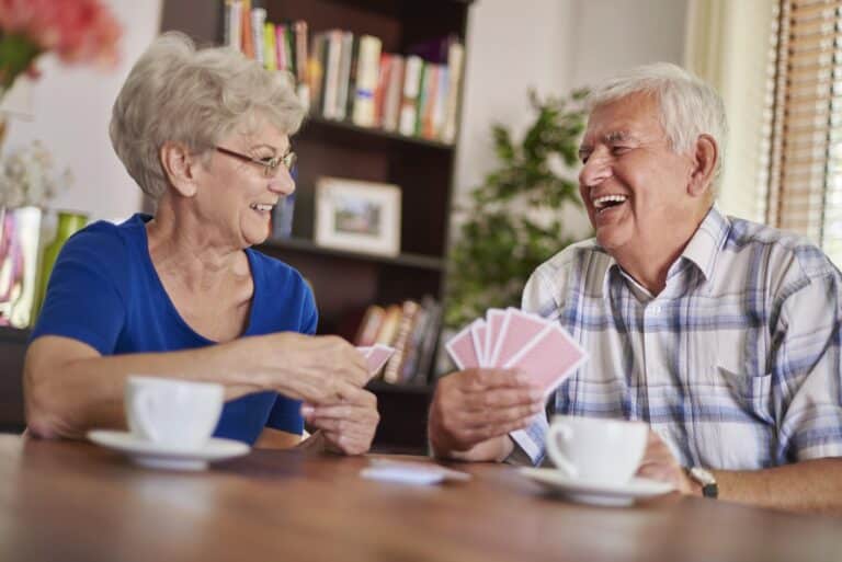 Two smiling seniors playing cards