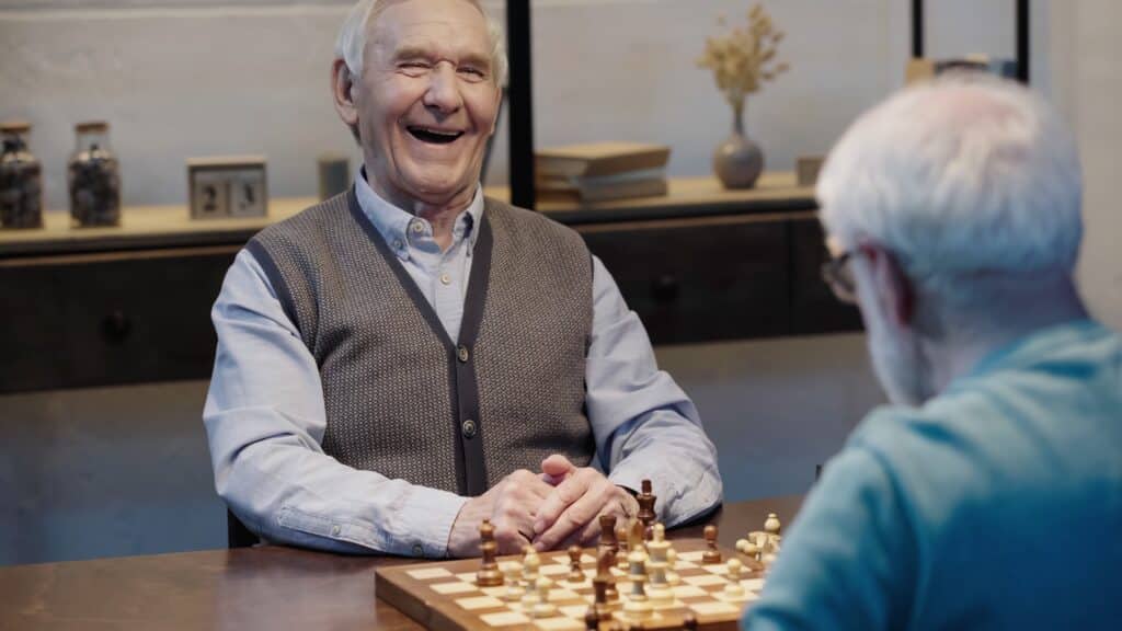 Senior man laughing while playing chess