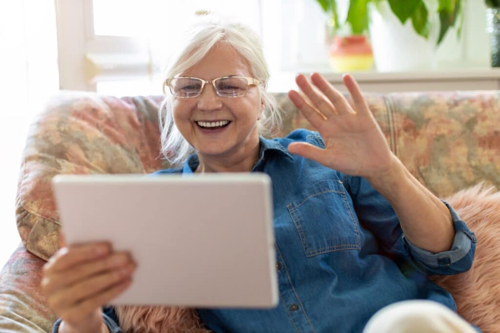 Senior woman smiling and video chatting using tablet