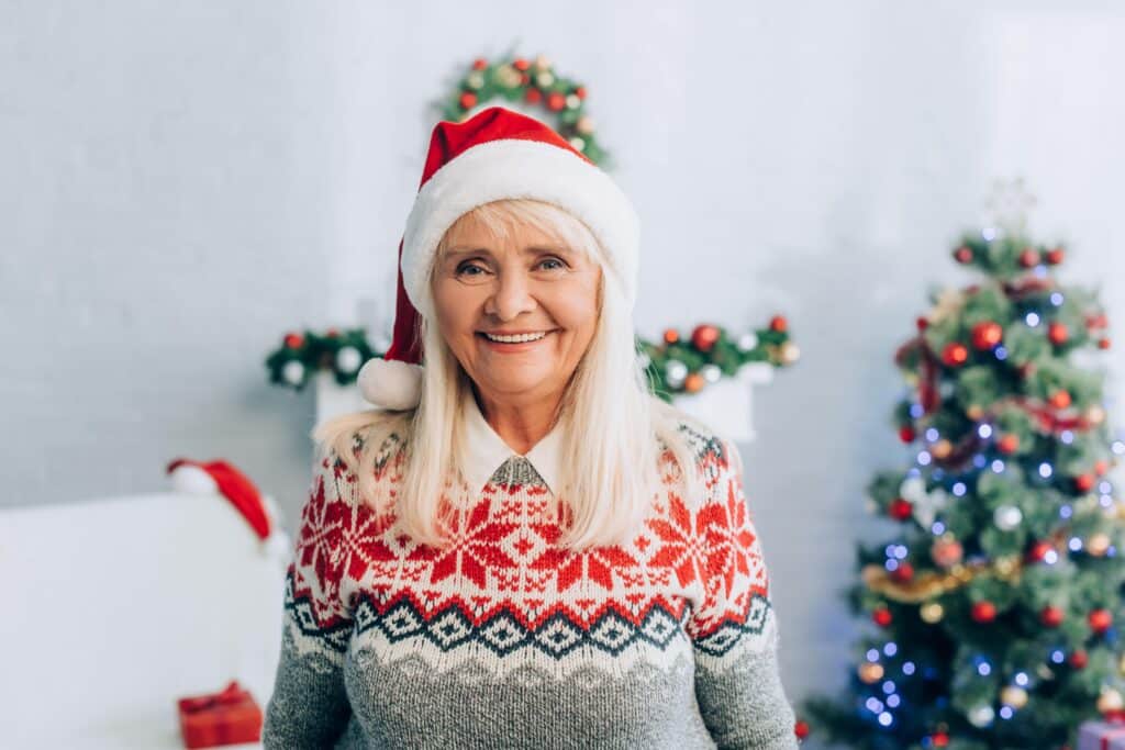 Smiling senior woman wearing christmas sweater and hat