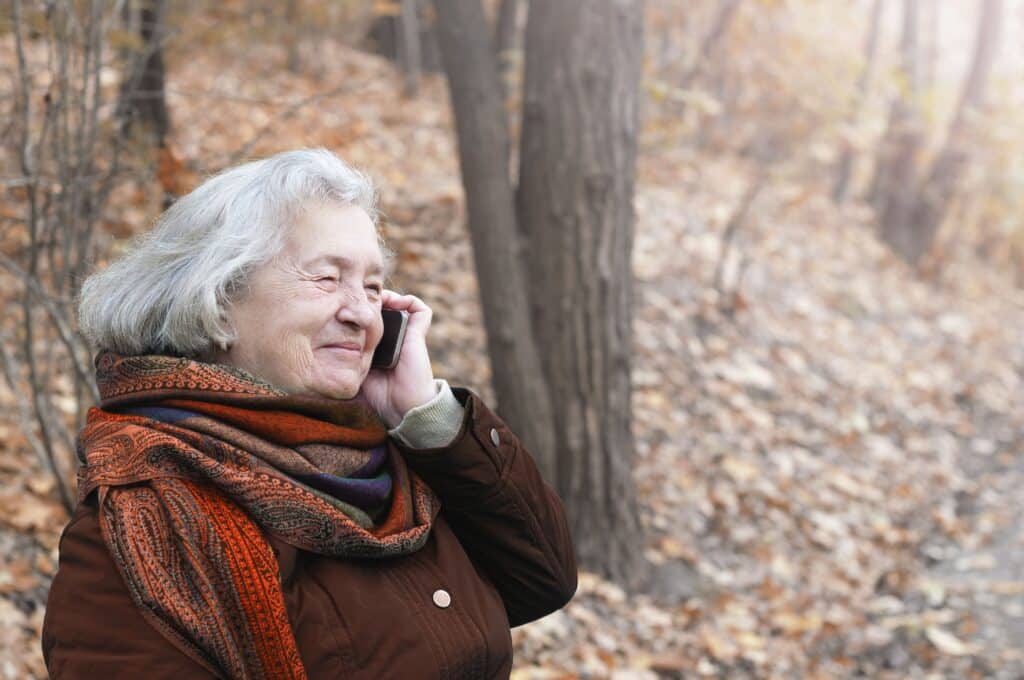 Smiling senior woman talking on phone while outside in winter