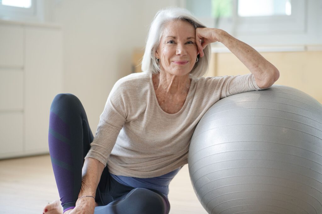 Smiling senior woman beside balance ball